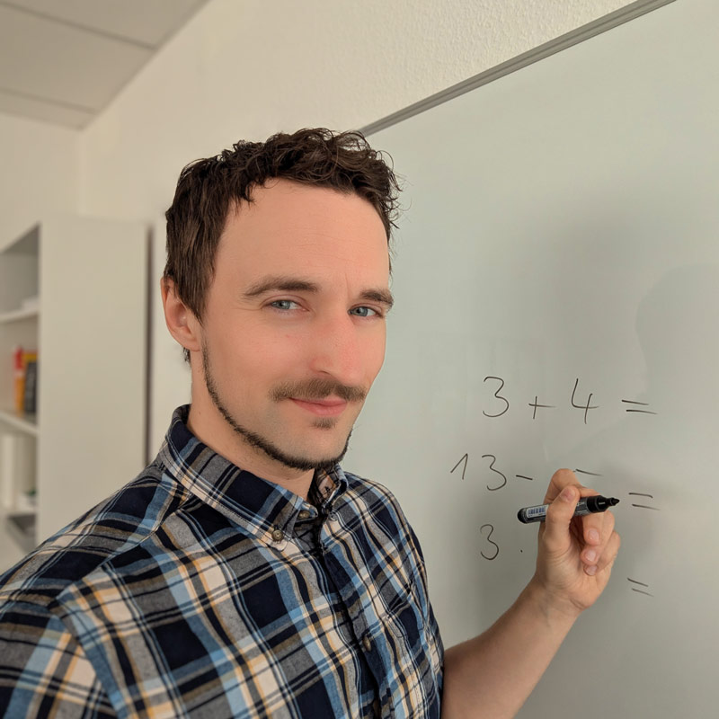 Porträt von Robert Jerchel wie er am Whiteboard steht und Mathenachhilfe gibt.